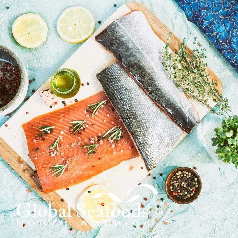 A mouth-watering image showcasing perfectly cooked pan seared salmon fillets with golden, crispy skin on a white plate, garnished with lemon wedges and fresh herbs