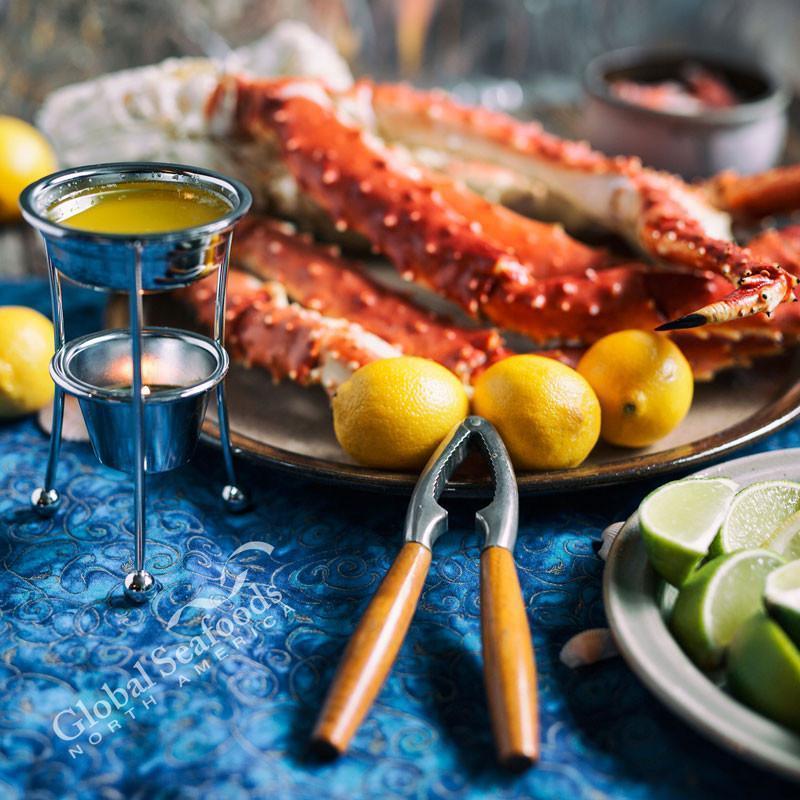 Roasted red crab clusters on a baking sheet garnished with fresh parsley and lemon wedges, ready to serve