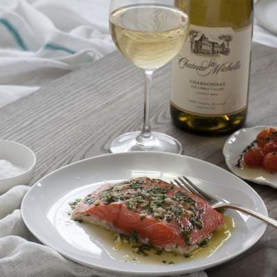Baked wild sockeye salmon fillet garnished with lemon slices and fresh dill on a white plate