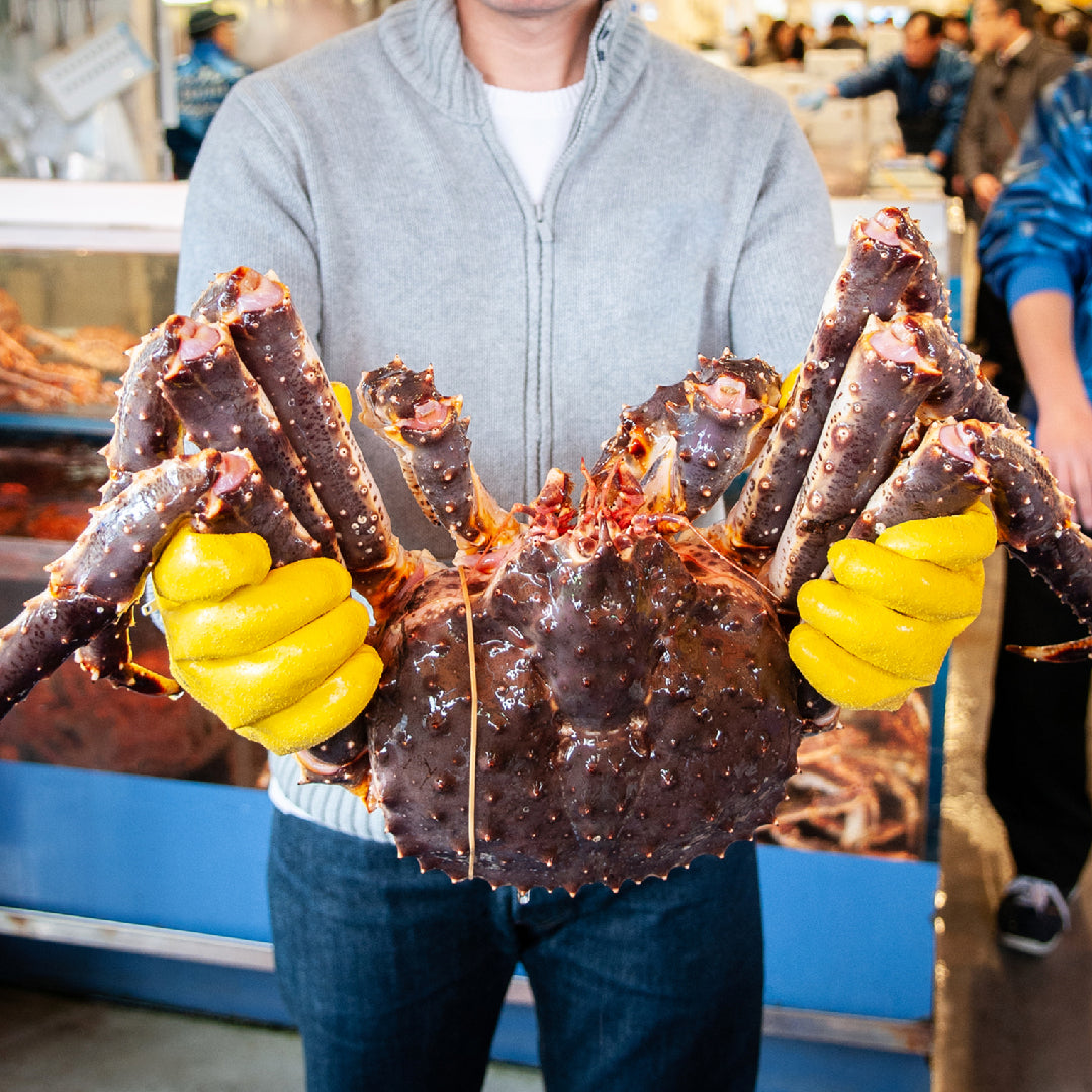 Jumbo Alaskan king crab legs cracked open to reveal sweet white meat, served with melted butter and lemon wedges on a wooden board