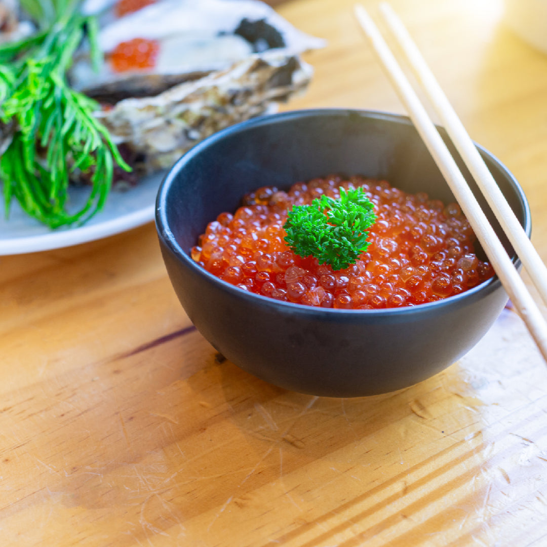 Ikura and avocado toast on whole-grain bread: creamy mashed avocado topped with vibrant orange salmon roe, microgreens, and a drizzle of olive oil