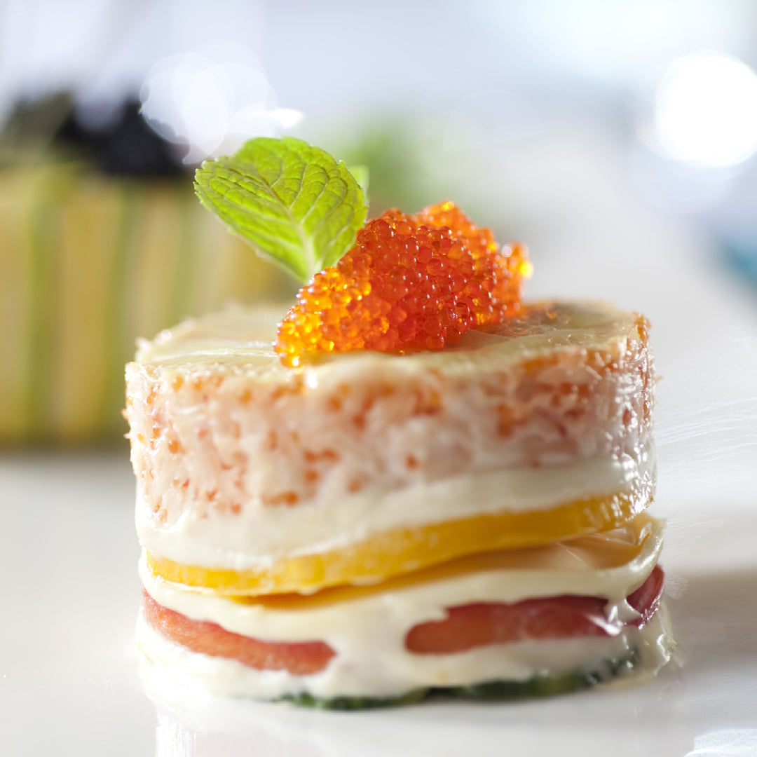 Salmon roe served on blinis with crème fraîche alongside a champagne flute, sake cup, and chilled vodka shot glass on an elegant table