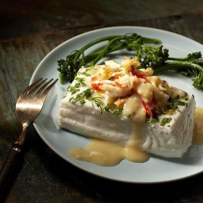 A tantalizing image of golden-brown broiled halibut fillets on a white plate, garnished with lemon slices and fresh herbs, showcasing the delicious outcome of the recipe