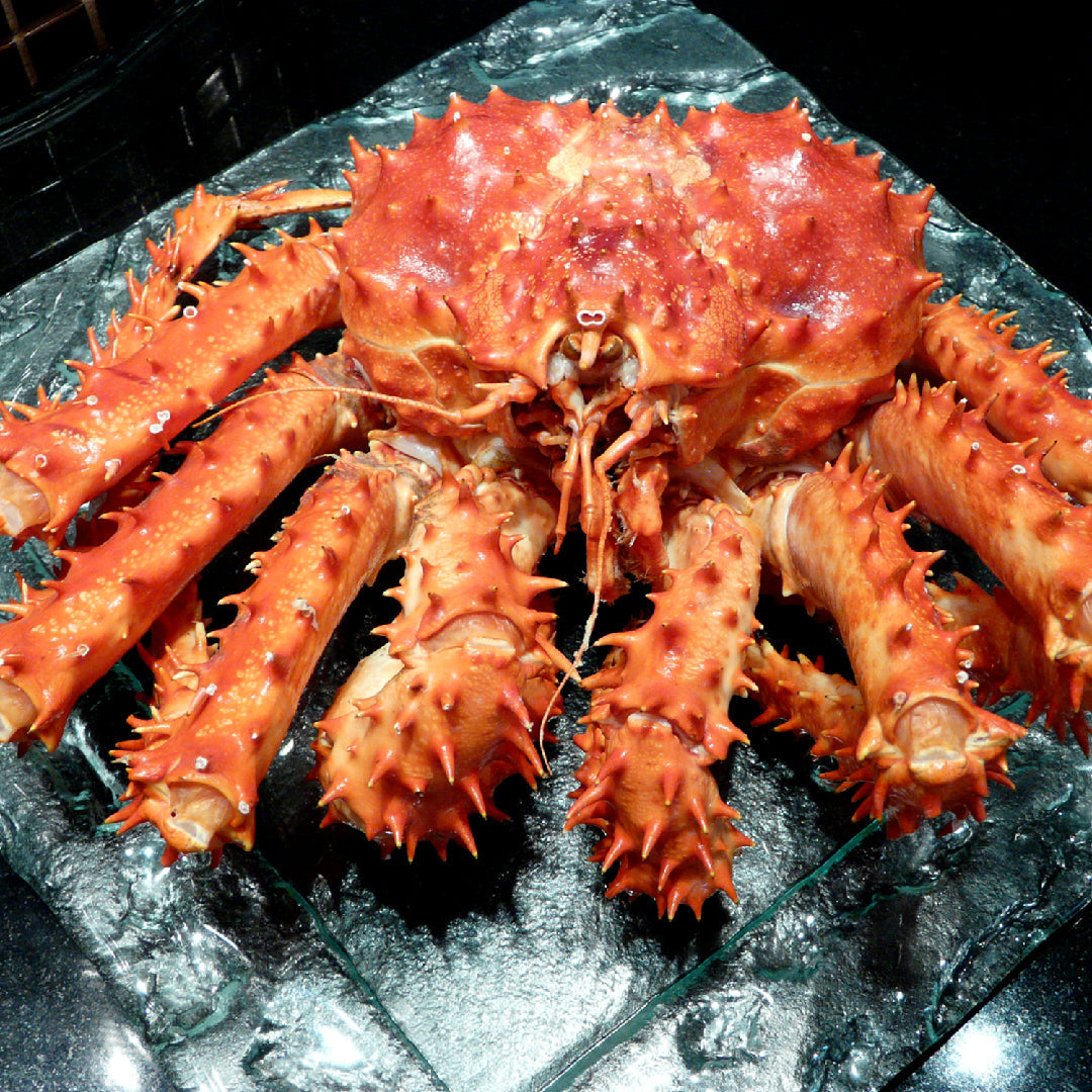 Jumbo Alaskan red king crab legs served with melted garlic butter and lemon wedges on a wooden board
