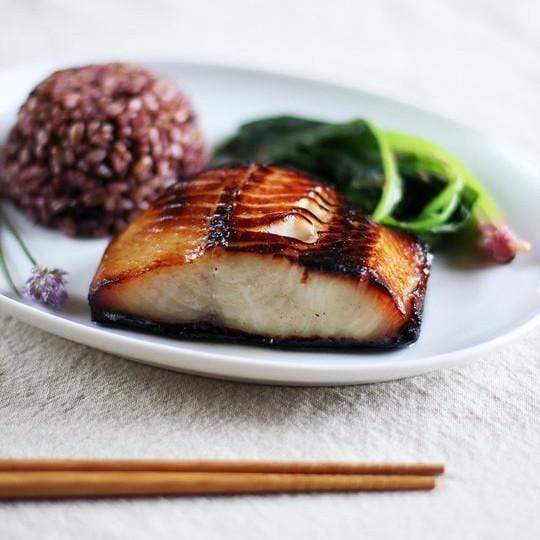 Nobu-style miso marinated black cod fillet with caramelized glaze served on a plate with green beans