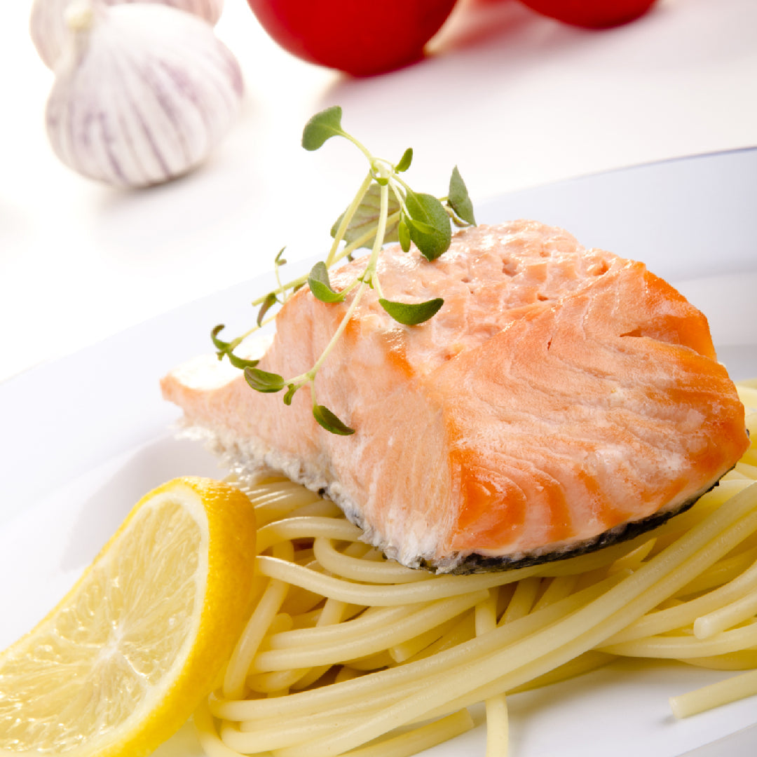 Golden-brown seared Ora King Salmon fillet in a cast-iron skillet with crispy skin and fresh herb garnish