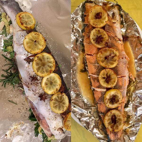Whole baked wild salmon with caramelized lemon slices and fresh herbs on a baking dish