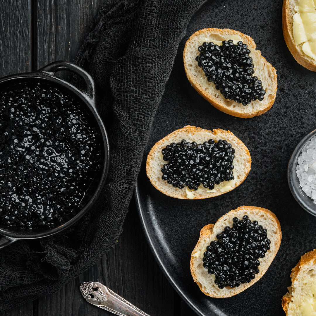 Premium Beluga caviar pearls in a classic tin on ice, with a mother-of-pearl spoon and champagne flutes in the background