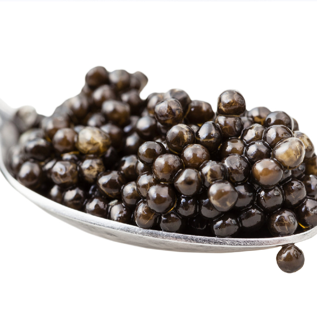 A plate of blinis topped with beluga caviar and sour cream, elegantly garnished with fresh dill