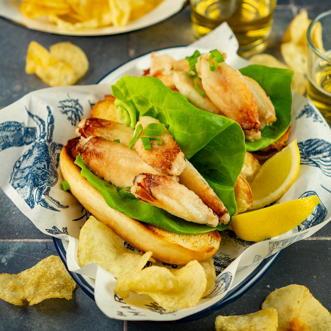 Golden-fried Dungeness crab cakes on a white plate with lemon wedges and tartar sauce