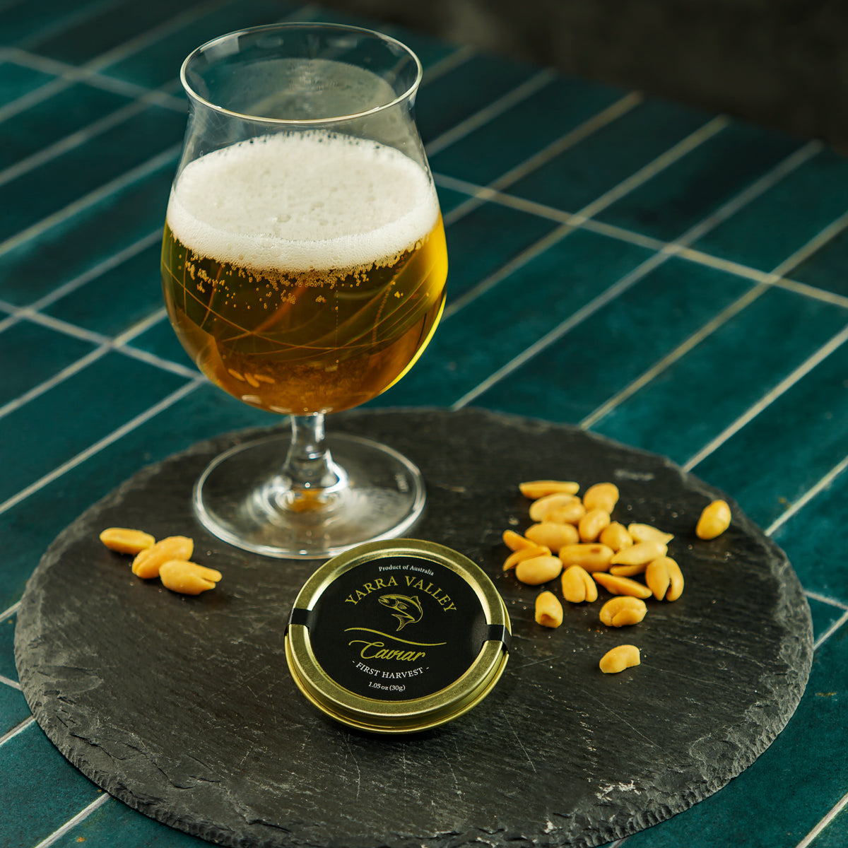 Vibrant orange-red chum salmon caviar pearls in a glass jar beside fresh dill and blinis on a dark slate board