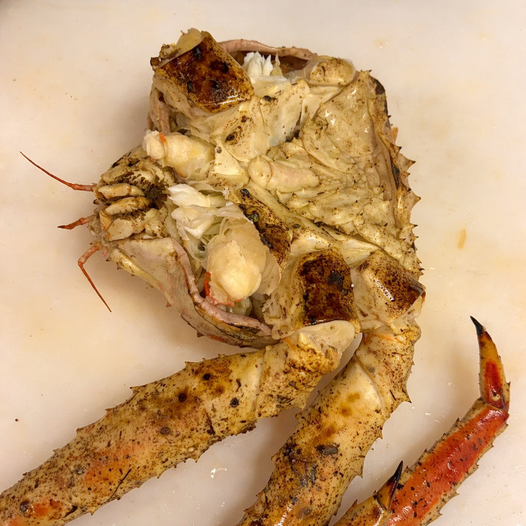 Hands cracking open a freshly cooked king crab leg with visible snow-white crab meat inside