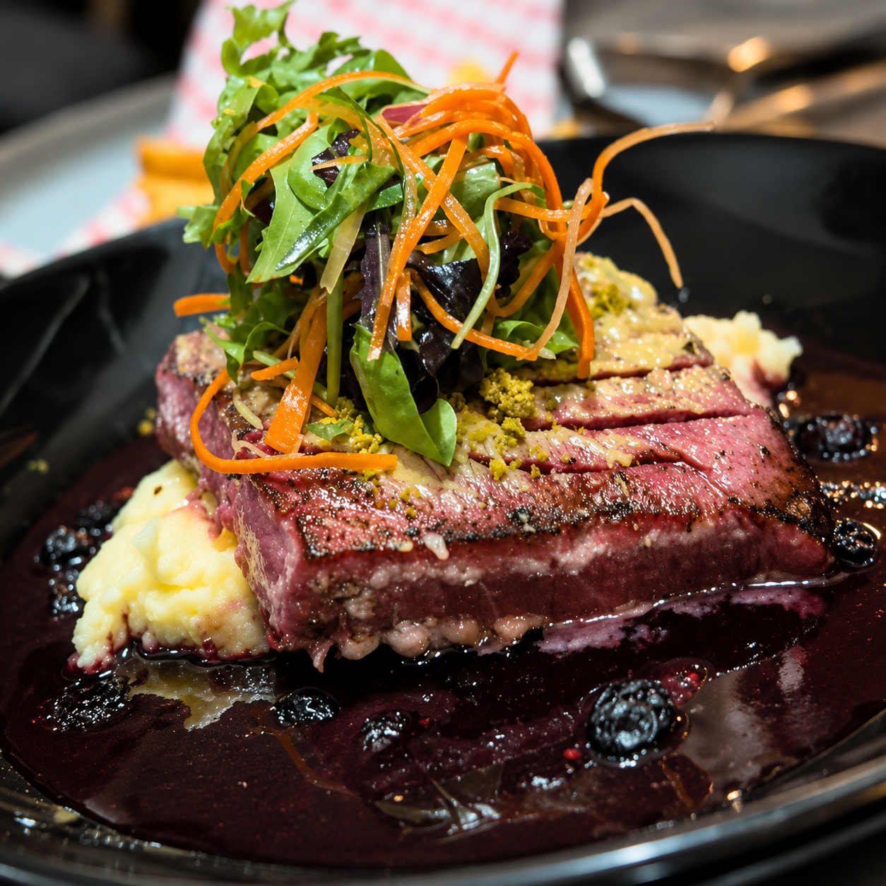Seared tuna medallions over mashed potatoes with blueberry reduction and crushed pistachios