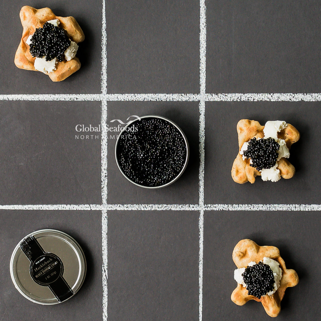 Pan-seared sea scallops topped with black caviar on parsnip puree with Parmesan cream sauce and orange reduction