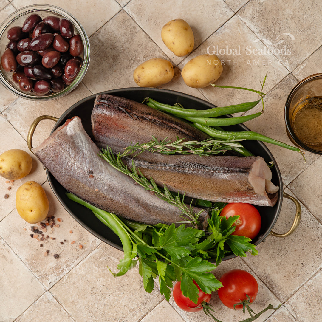 Side-by-side comparison of hake and cod fish fillets on a cutting board