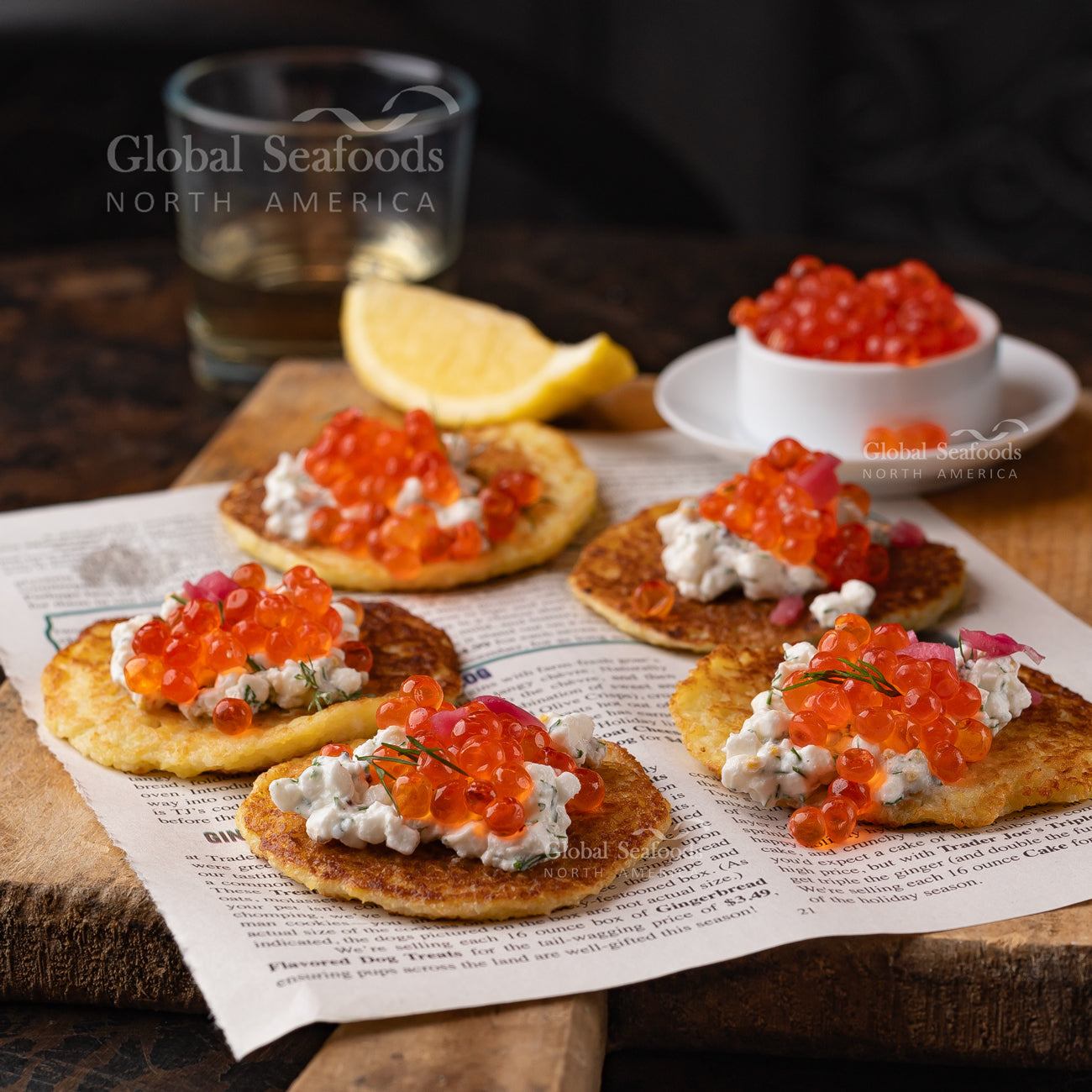 Small blini topped with red caviar, served on a white plate as an elegant appetizer.