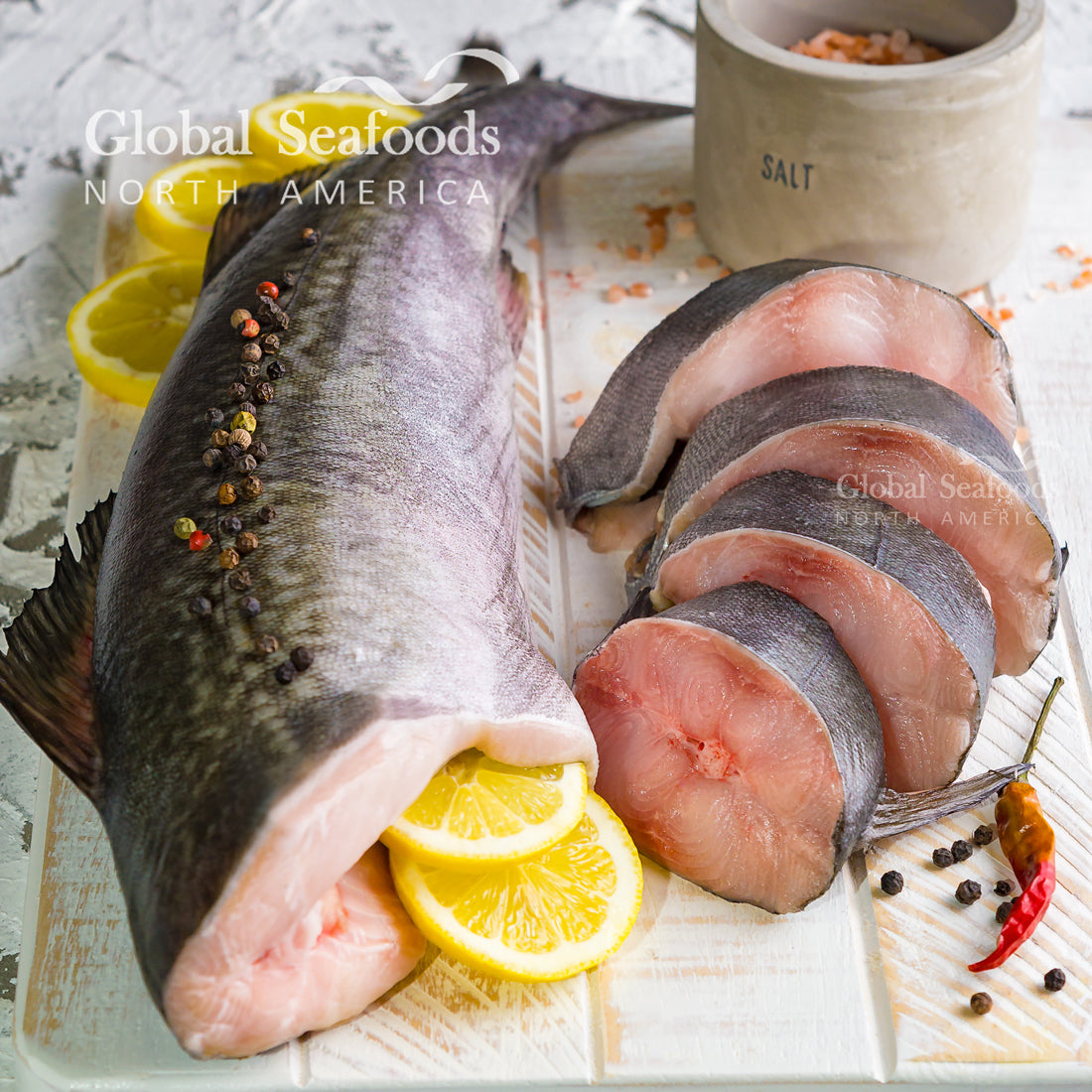 Baked sablefish fillet garnished with lemon slices and fresh herbs on a serving plate