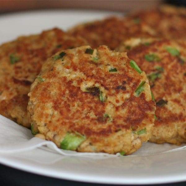 Freshly made classic salmon cakes on a white plate, garnished with lemon slices and parsley, ready to be served
