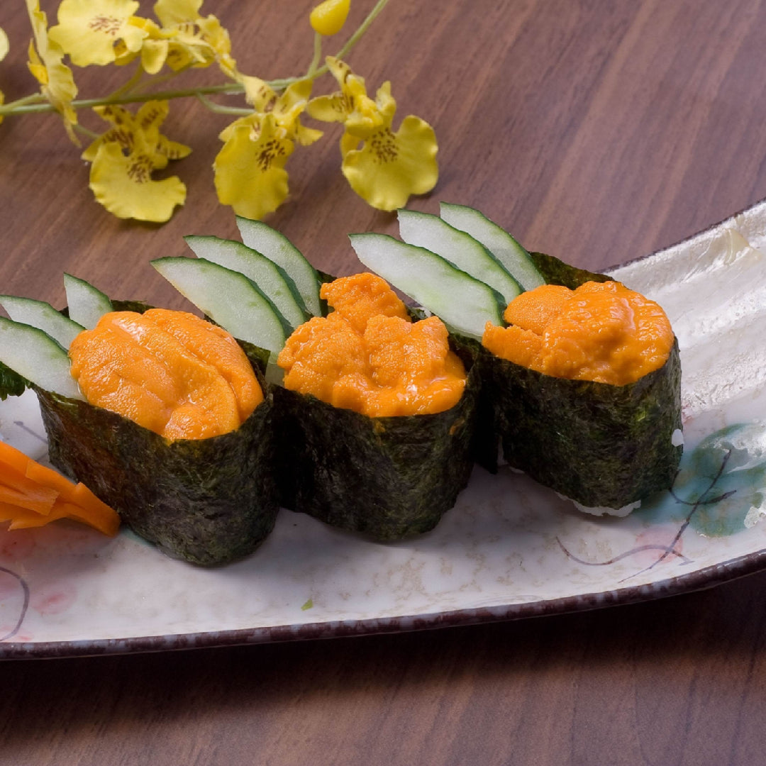 Creative sea urchin uni sushi rolls and nigiri arranged on a Japanese slate board with garnishes