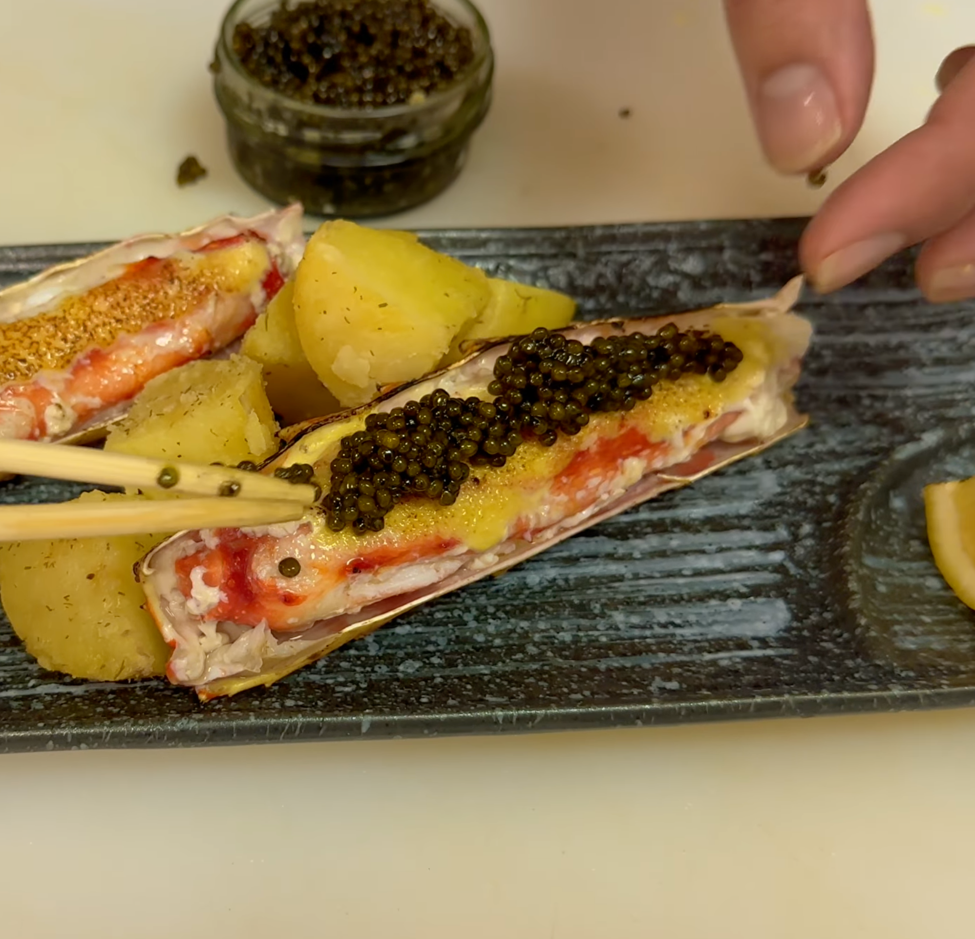 Seared king crab legs topped with sturgeon black caviar on a white plate with garlic potatoes
