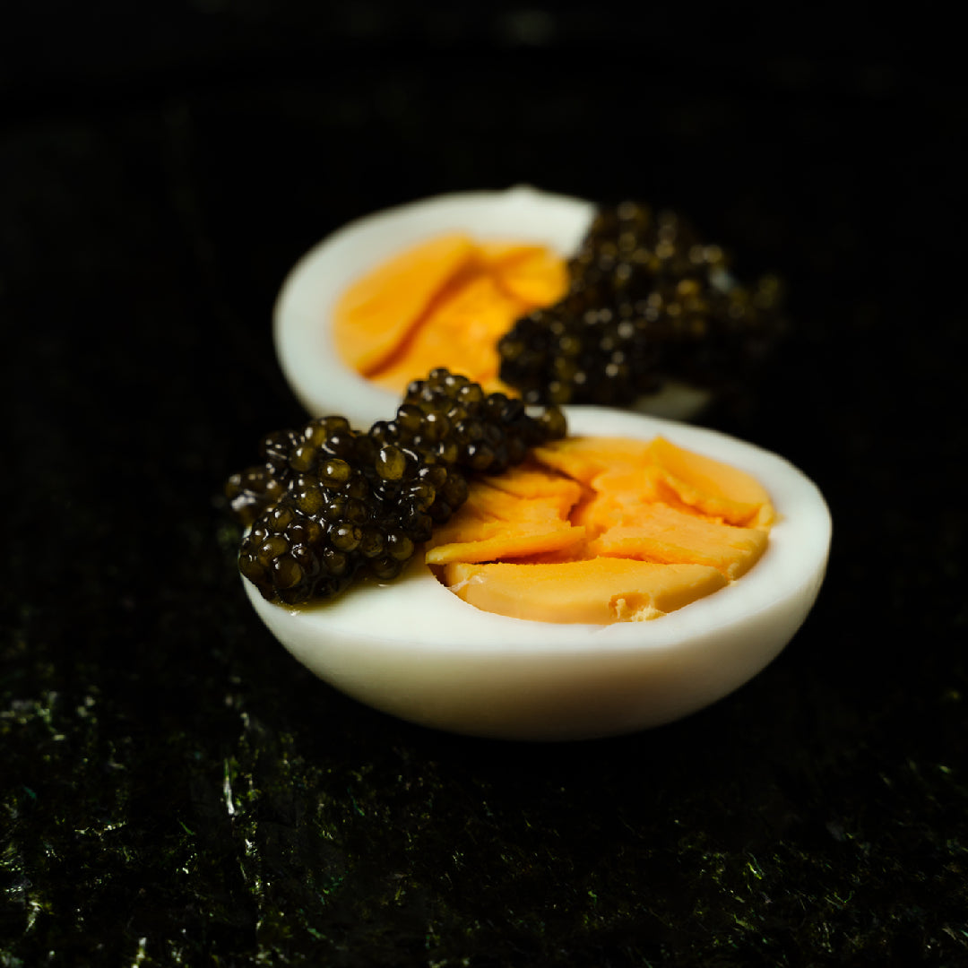 Side-by-side comparison of Grade 1 and Grade 2 Beluga caviar eggs in mother-of-pearl spoons