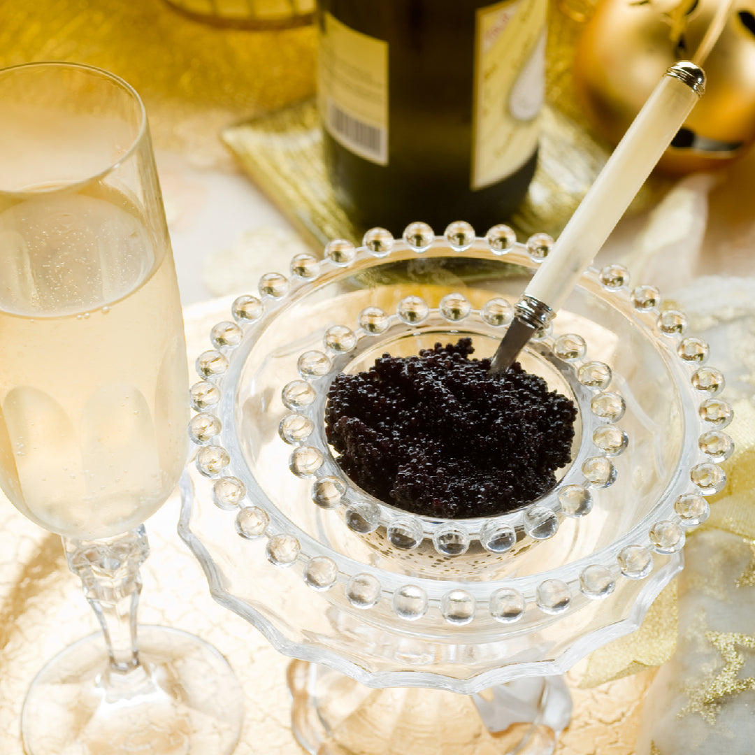 Glass jar of black caviar stored on ice in a refrigerator
