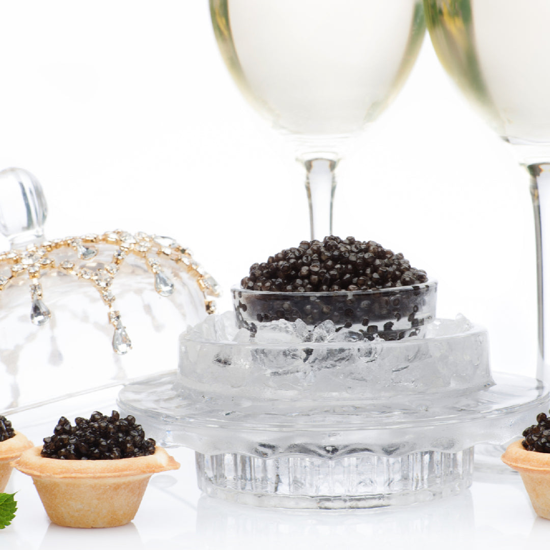 Side-by-side comparison of Beluga caviar (large, light gray pearls) and Osetra caviar (medium, golden-brown pearls) served on mother-of-pearl spoons