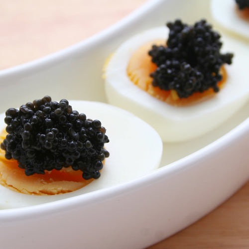 Beluga caviar pearls served on a mother-of-pearl spoon with blinis and crème fraîche