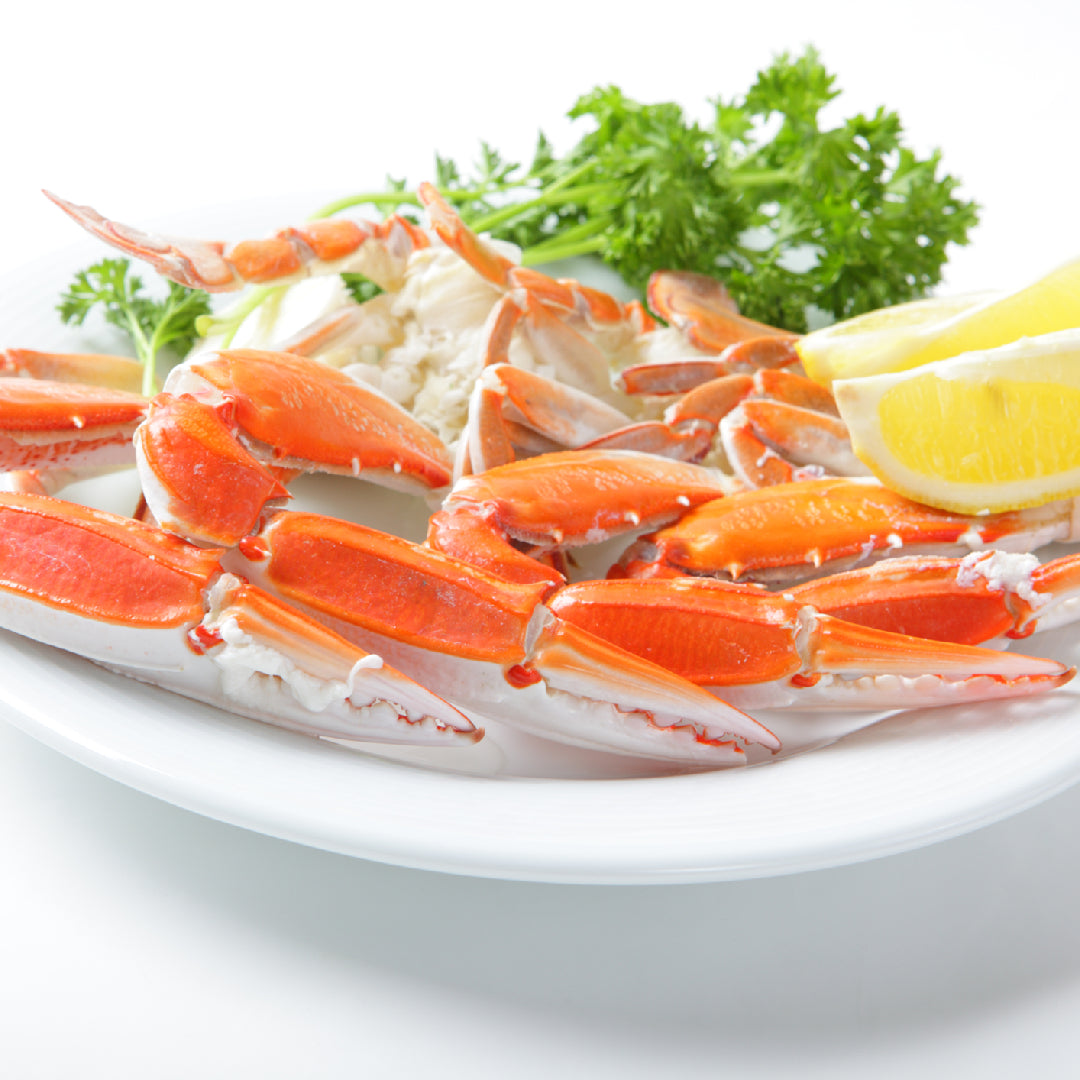 Bowl of creamy crab claw bisque garnished with fresh chives and whole crab claws on an elegant table setting