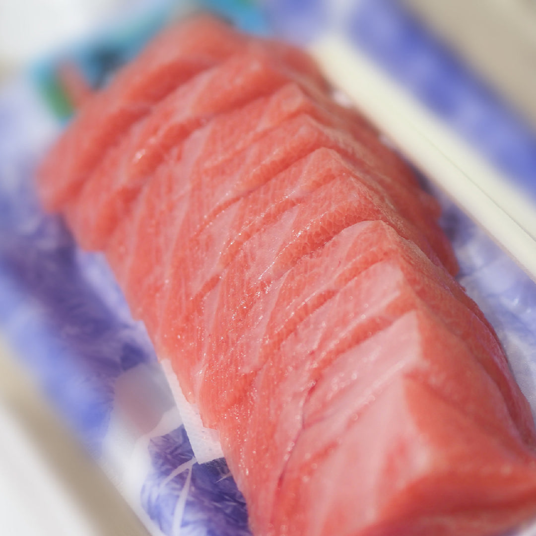 Side-by-side comparison of deep red bluefin tuna and light pink albacore tuna fillets on a wooden board