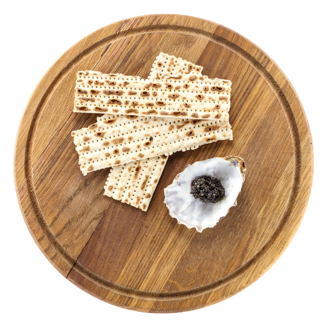 Kaluga caviar served on crushed ice in a tin with mother-of-pearl spoons, blinis, crème fraîche, and a glass of champagne on an elegant table
