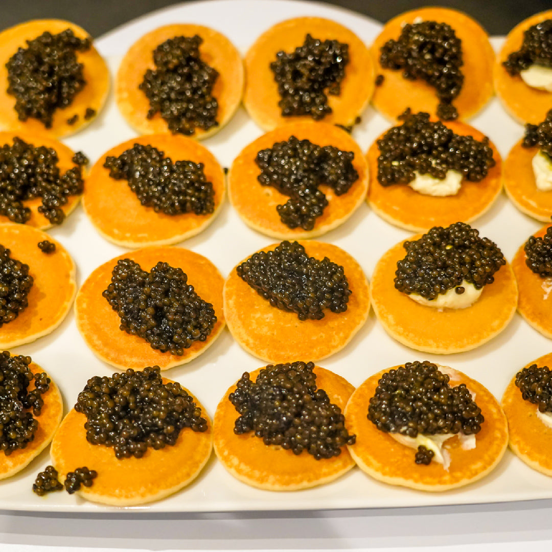 Kaluga caviar pearls in a tin on crushed ice with blinis and lemon, highlighting the health and gourmet benefits of this luxury delicacy