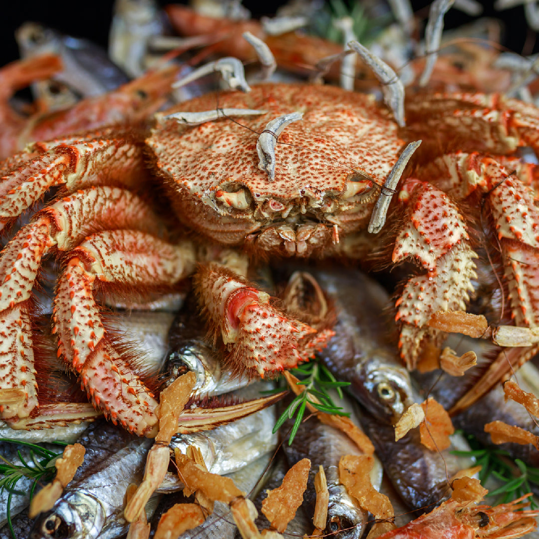 A romantic crab boil date night setup with steamed crab legs, garlic butter dipping sauce, candles, and wine on a parchment-covered table