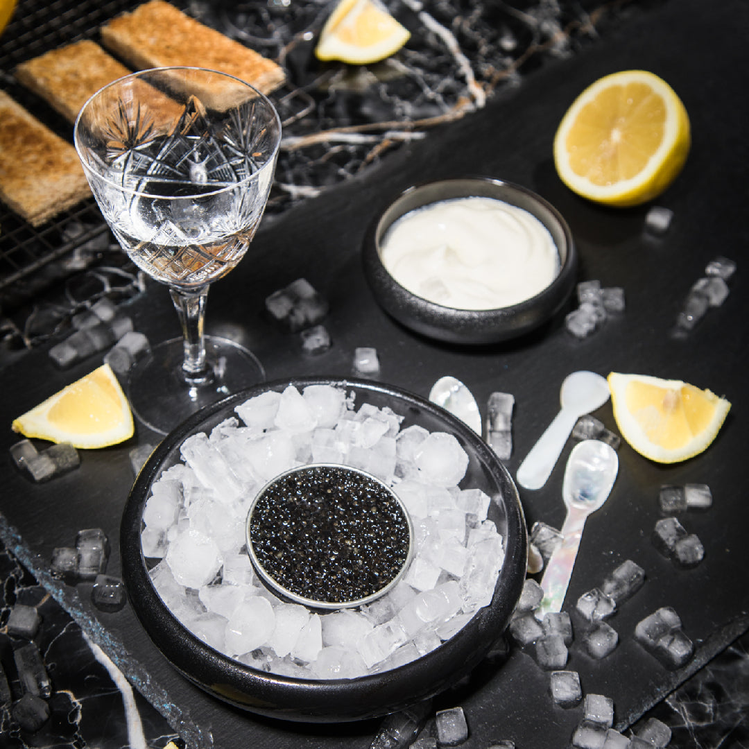 Beluga caviar pearls served on a mother-of-pearl dish with blinis and chives at an elegant dinner setting