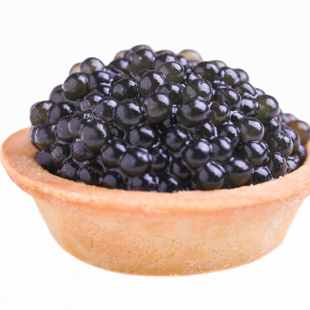 Beluga caviar in a tin surrounded by crushed ice, mother-of-pearl spoon, and blinis on a dark luxury surface