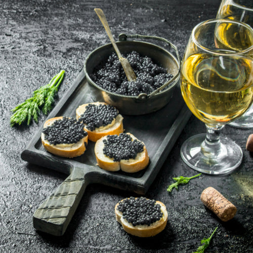 Premium malossol caviar in an open tin displayed on crushed ice with a mother-of-pearl spoon