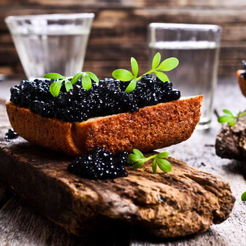 Premium sturgeon fish caviar pearls served on crushed ice with blinis and crème fraîche