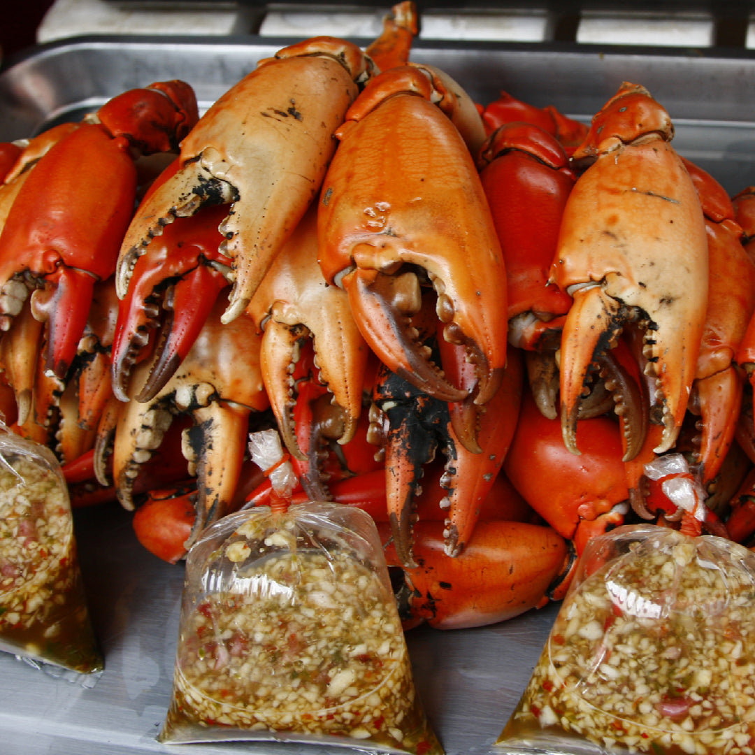 Assorted crab claws on a seafood platter: Alaskan King Crab claws, Jonah Crab claws, and cocktail crab claws with dipping sauces and lemon wedges