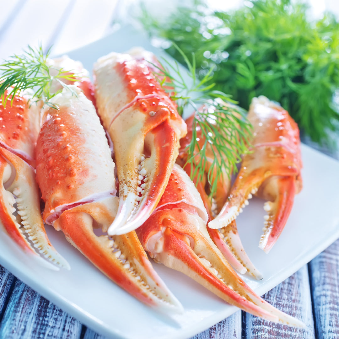 Ten crab claw dishes arranged as a spread: grilled King Crab claws with garlic butter, chilled cocktail claws with aioli, Jonah Crab bisque, and crab linguine