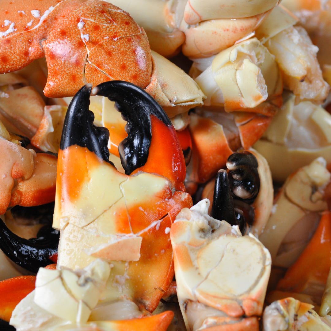 Alaskan King Crab claws and Jonah Crab claws arranged on a seafood platter with lemon wedges, cocktail sauce, and garlic butter dipping bowls