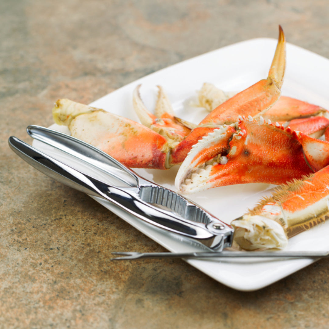 Stainless steel crab crackers and seafood picks on a wooden board