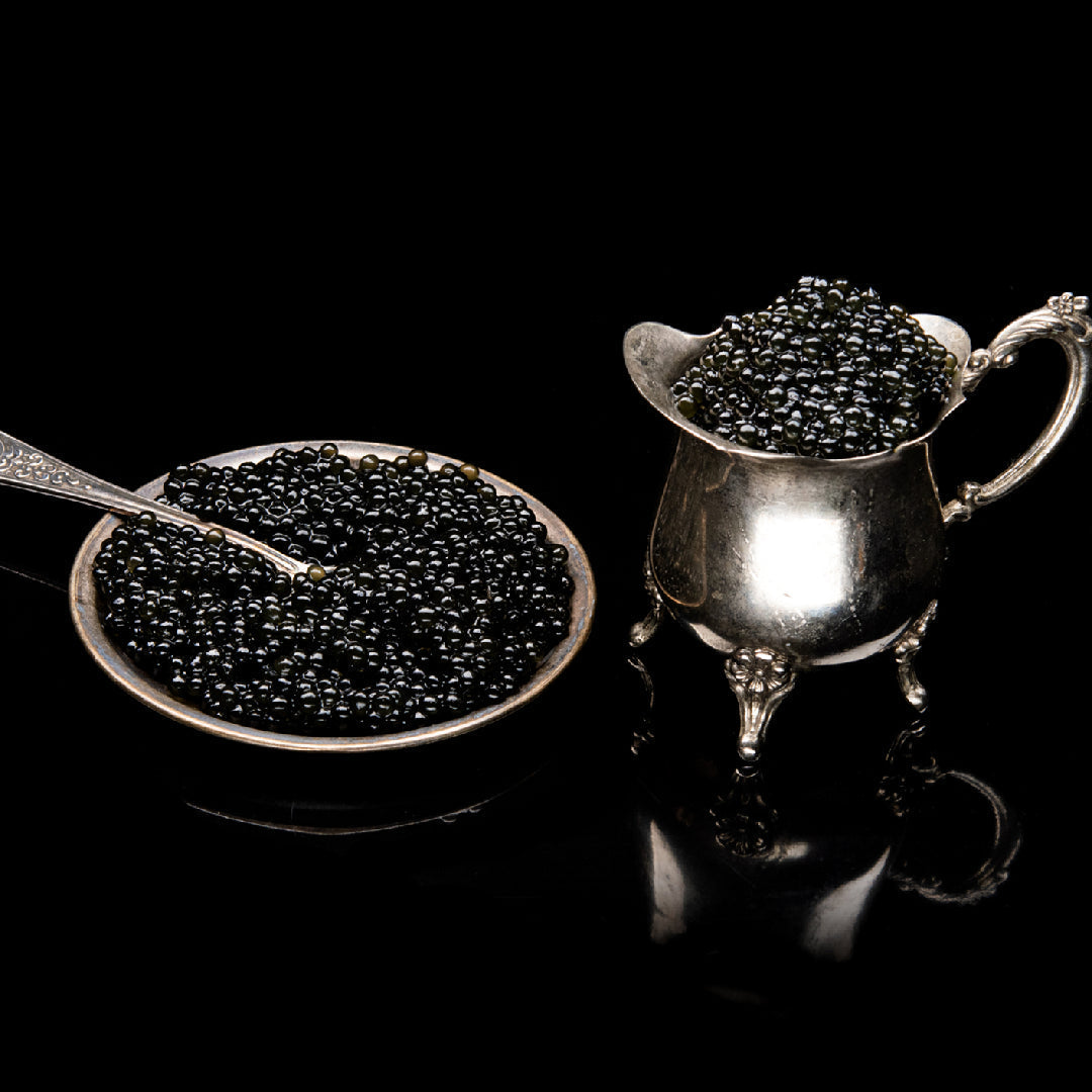 Blanc de Blancs Champagne poured beside an open tin of Beluga caviar pearls on a white marble surface