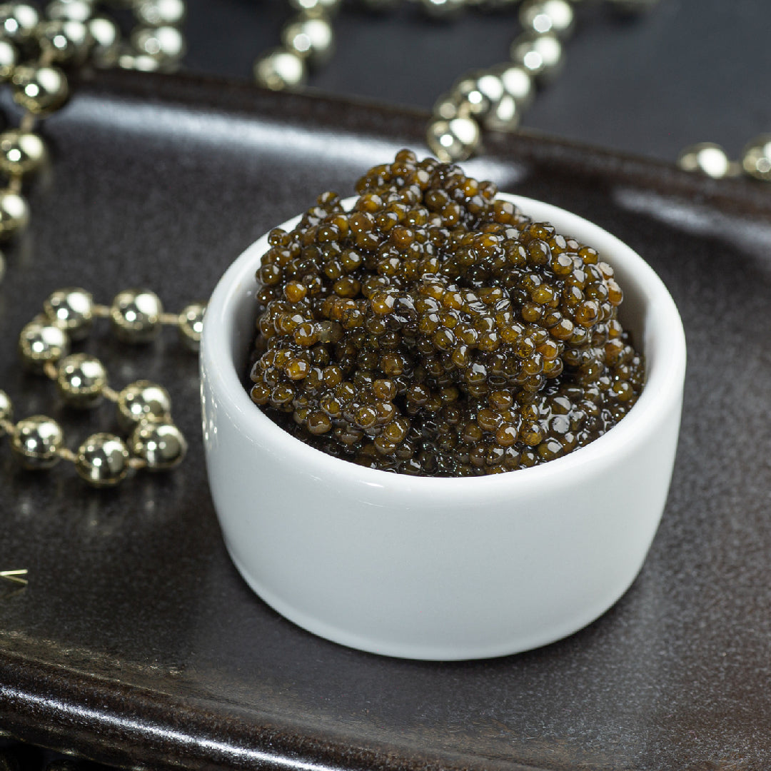 Chilled vodka shot glass alongside a tin of Osetra caviar served on crushed ice