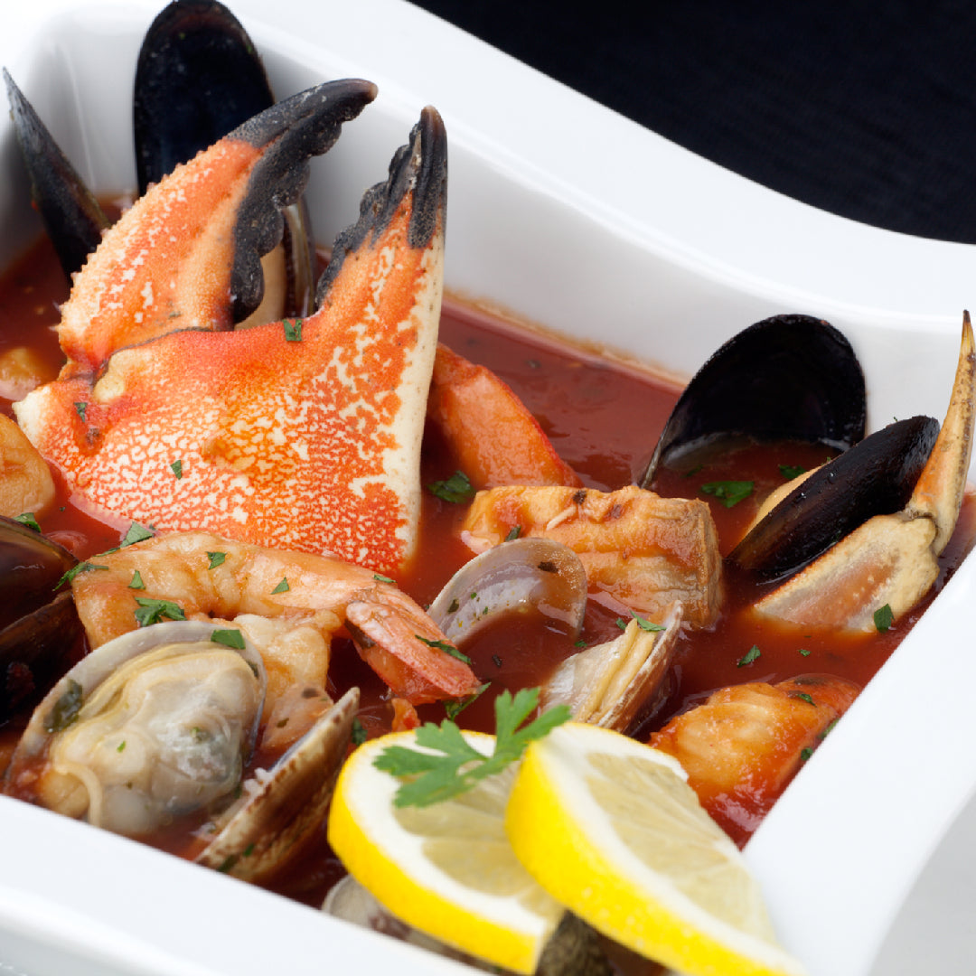 Five gourmet crab claw dishes including garlic butter claws, spicy pasta, chilled salad, risotto, and tacos arranged on a seafood spread