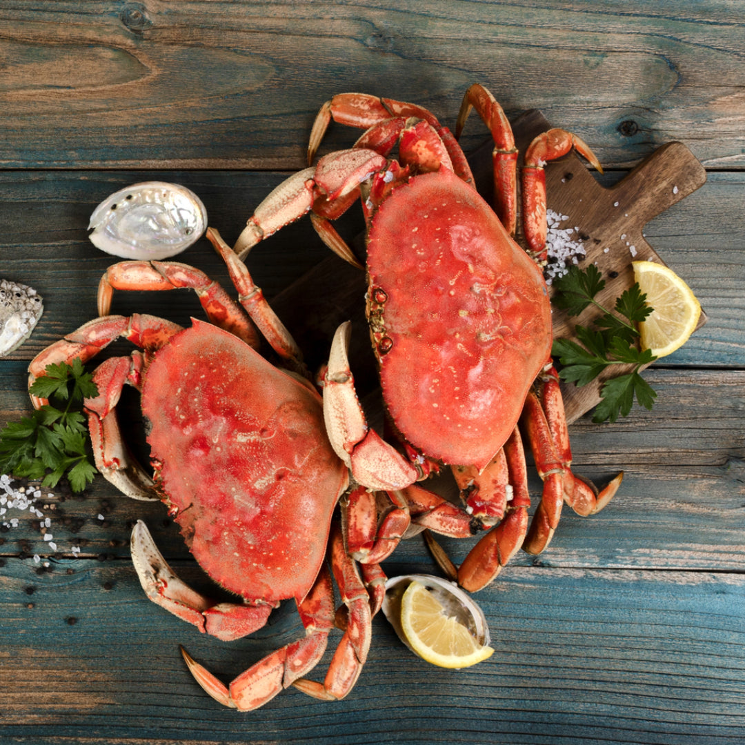 Chilled white wine glass beside a plate of steamed Dungeness crab legs with lemon and butter