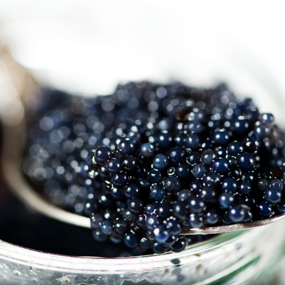 Glistening golden caviar pearls served in a crystal dish on crushed ice with a mother-of-pearl spoon