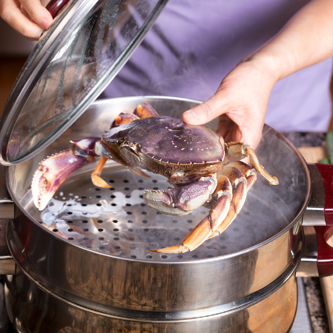 Cooked Dungeness crab legs on a serving platter with lemon wedges and melted butter dipping sauce