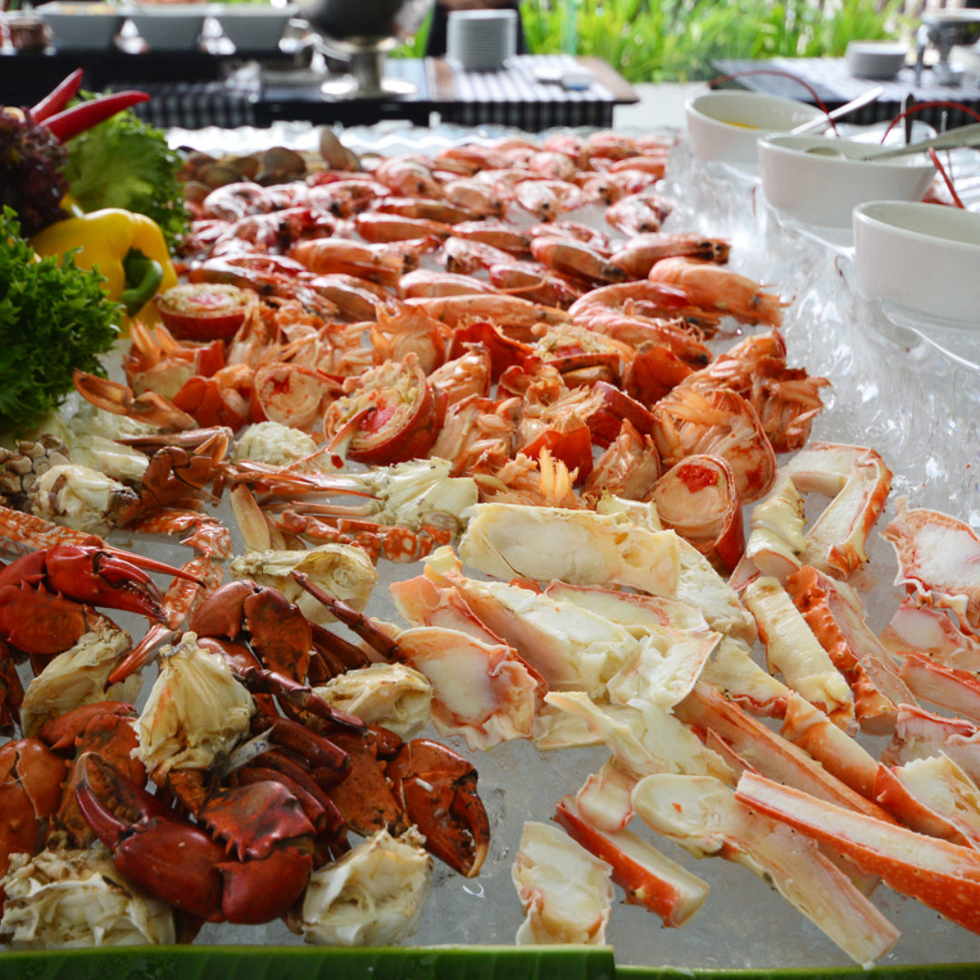 King crab legs and snow crab clusters piled on a seafood buffet spread with drawn butter, lemon wedges, and cocktail sauce