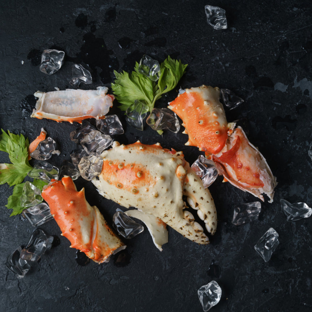 Variety of crab meats displayed on ice, showcasing different types such as Blue, Dungeness, and King crab, with labels indicating their grades from Jumbo Lump to Claw