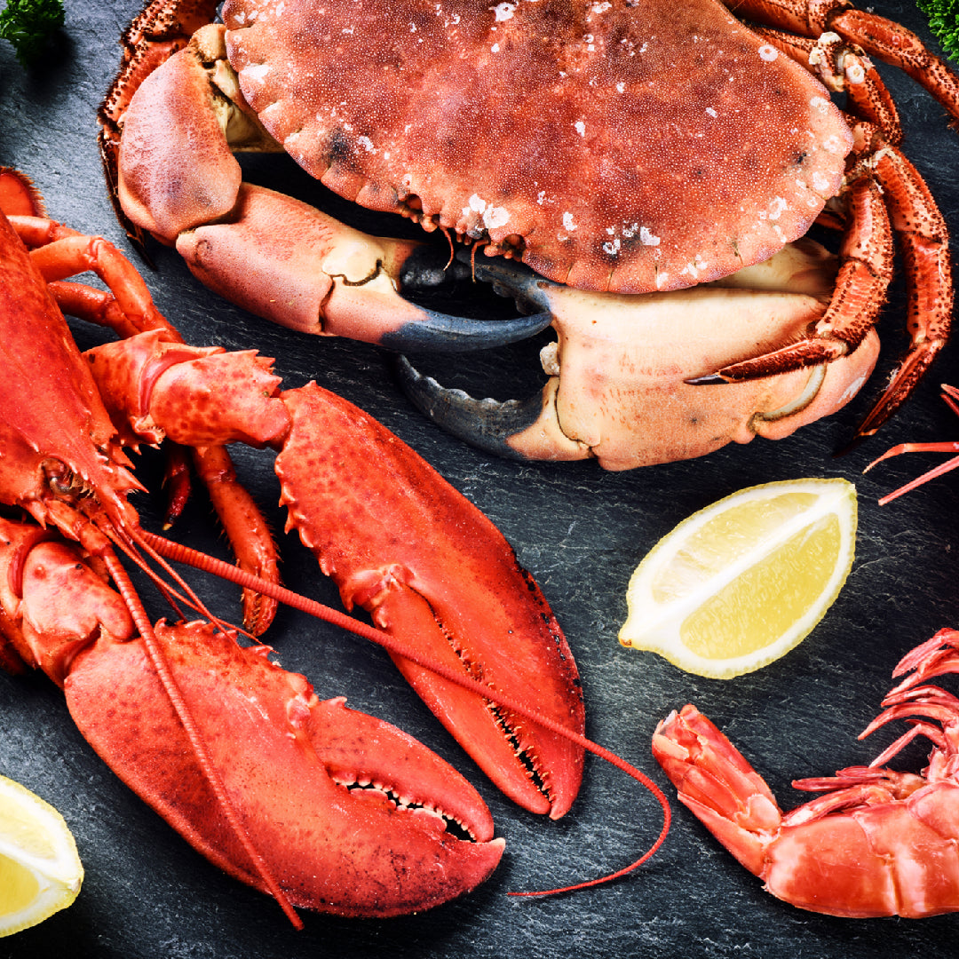Side-by-side comparison of a blue Sebastian crab and a red lobster on a seafood market display with ice